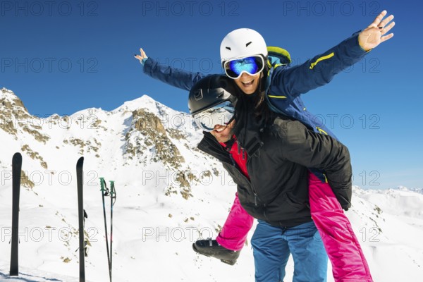 Happy caucasian skiers couple in love having fun arms outstretched together playing in mountains