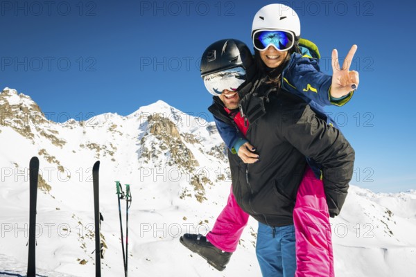 Young happy caucasian couple portrait together piggyback hug enjoying looking at camera in snowy