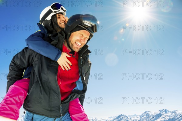 Couple skiers piggyback having fun hugs enjoy winter holidays outdoors in ski resort with eyes