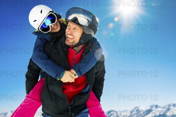 Romantic happy skiers couple in love having fun together playing in mountains piggybacking at