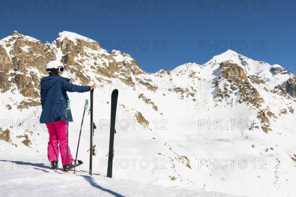 Young caucasian woman pose looking at snowy mountains range in winter. Get away skiing holidays