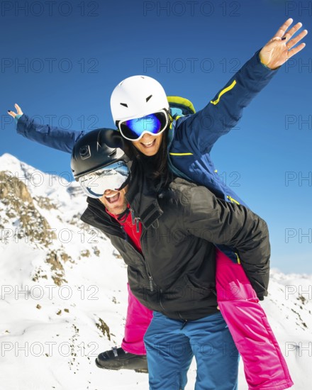 Happy young caucasian skiers couple in love having fun together playing in mountains piggybacking
