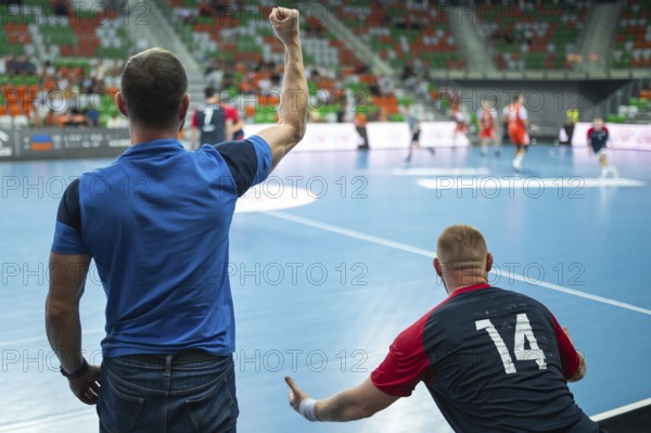 View form the behind on head coach and substitutions bench with handball match in background.