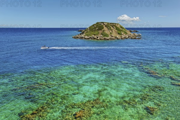 Small island Vrachonisida in front of the Grande Blue Beach in the turquoise blue sea with passing