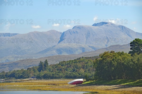 An overturned boat in front of an impressive mountain backdrop in fine weather, view of Ben Nevis,