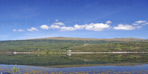 A clear lake reflects the surrounding mountains and cloudy sky, Caledonian Canal, Fort William,