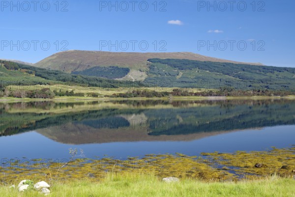 A loch with a clear reflection of mountains under a bright blue sky, Loch Eil, Scotland, Great