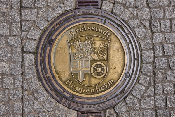 Manhole cover, district town of Heppenheim, golden, pavement made of paving stones, rain gutter,