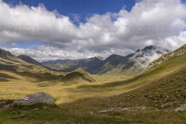 View from Passo del Sole in Alpe Carorescio with Piano Grande plateau and hiking trail marker,