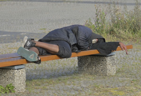Homeless man sleeping on a bench, Ernst-Reuter-Platz, Charlottenburg, Berlin, Germany ! Personal