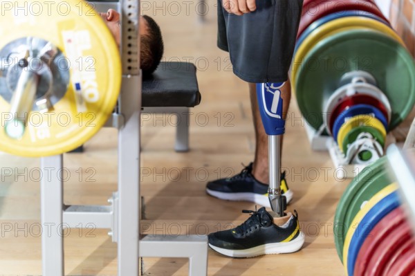 Adaptive athlete with a prosthetic leg doing weightlifting exercises on a gym bench, demonstrating