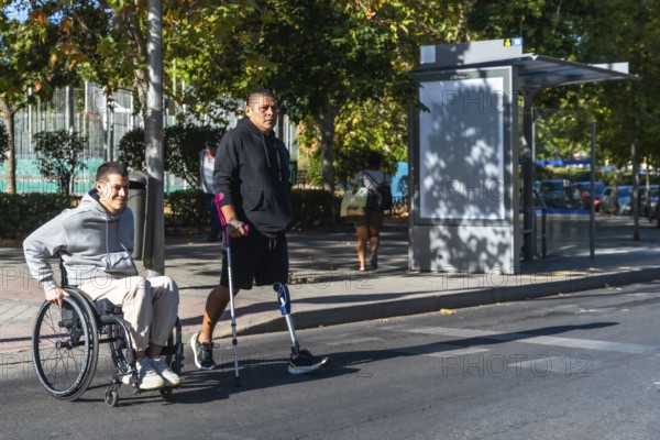 Two amputee men, one using a wheelchair and the other a prosthetic leg with crutch, navigating an