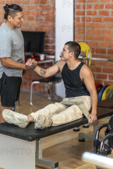 Two men shaking hands in a gym as a trainer supports an adaptive athlete with a prosthetic leg and