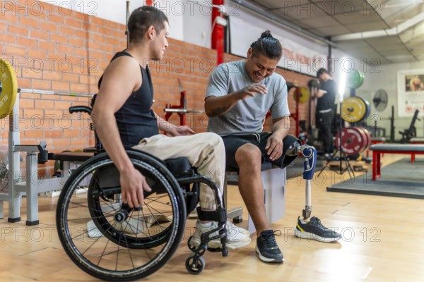 Two young men with disabilities one in a wheelchair, one with a prosthetic leg laughing and bonding