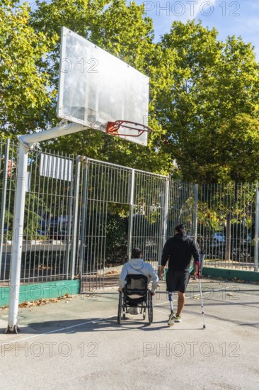Disabled men on an outdoor basketball court, one in a wheelchair and another with a prosthetic leg