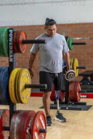 Man with prosthetic leg training at the gym, carrying heavy weights, demonstrating strength,