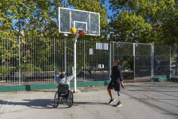 Men with prosthetic leg and wheelchair playing basketball outdoors, demonstrating inclusion,