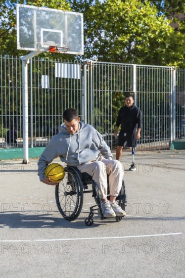 Young men with physical disabilities engaging in adaptive basketball. One person using a wheelchair
