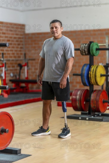 Male amputee athlete standing confidently in a gym, showcasing his prosthetic leg and symbolizing