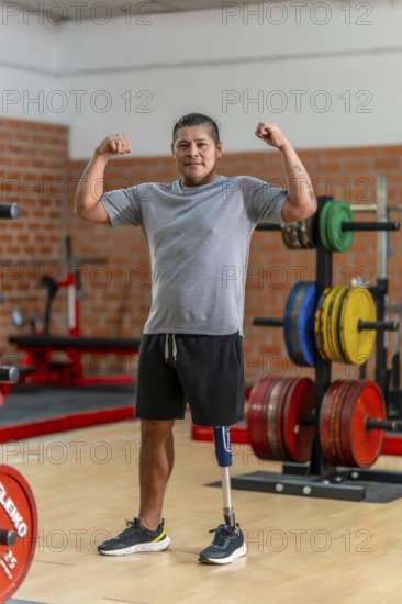 Amputee man with a prosthetic leg standing confidently in a gym, flexing his biceps and looking at