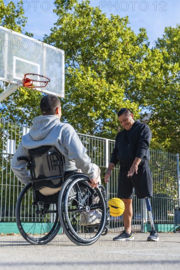 Men with a wheelchair and a prosthetic leg are happily dribbling a yellow basketball on an outdoor