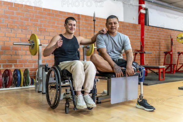 Two adaptive athletes standing together in a gym, one man uses a wheelchair and the other has a