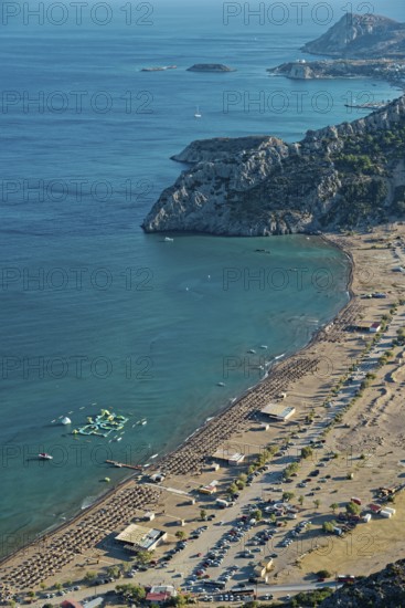 View of the sunny coastal landscape of Tsambika with sandy beach, blue sea and cliffs, Church of