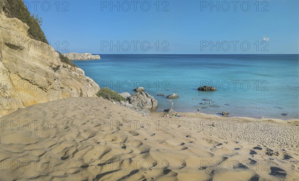 Tsambika beach with fine sand and large rocks on a sunny day, azure blue water and clear sky,