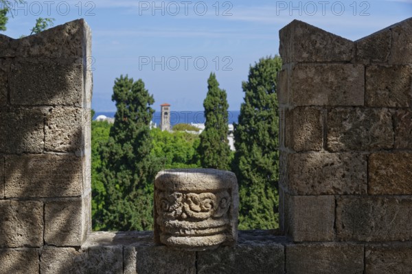View from a stone wall with battlements of green trees and the distant sea under a blue sky, Grand