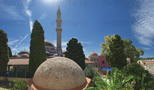 A minaret with domes and trees against a bright blue sky in a summer atmosphere, Suleiman Mosque,