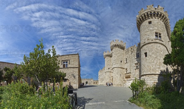 Wide view of a medieval castle with towers and stone walls under a cloudy sky, Grand Master's