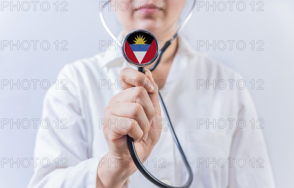 Female doctor holding stethoscope with Antigua and Barbuda flag. National health system of Antigua