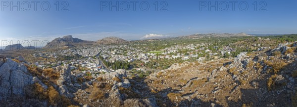 Panoramic view of the town of Archangelos in the middle of a vast and sunny mountain landscape,