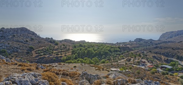 View over a barren range of hills near Stegna to the sea under the morning sun, Stegna,