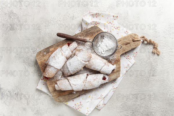 Bagels with filling, sweet pastries, sprinkled with powdered sugar, on a wooden board, dessert,