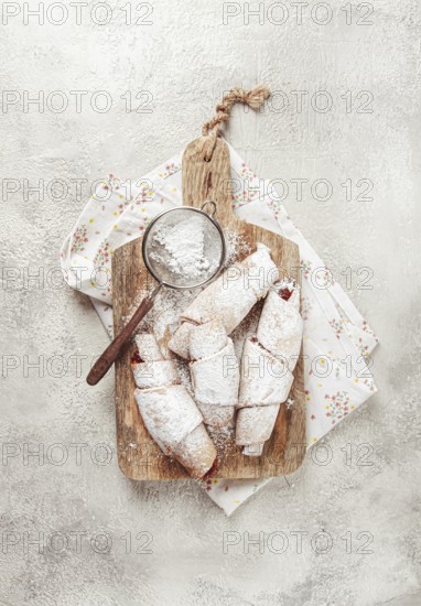 Bagels with filling, sweet pastries, sprinkled with powdered sugar, on a wooden board, dessert,