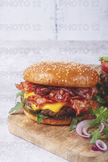 Burger with beef and bacon, with arugula and caramelized onions, pickles, sauce, homemade, no