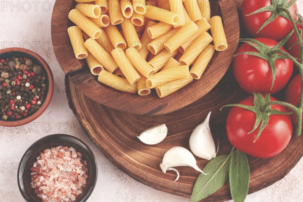 Pasta ingredients spread out, on a wooden surface, with tomatoes and spices, ready to cook, there