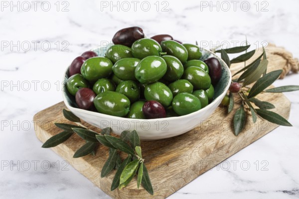 Chalkidiki olives, classic Greek green olives, in a bowl on a cutting board, top view, without