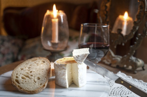 Chaource cheese presented sliced with bread and red wine in warm candlelight, typical of the