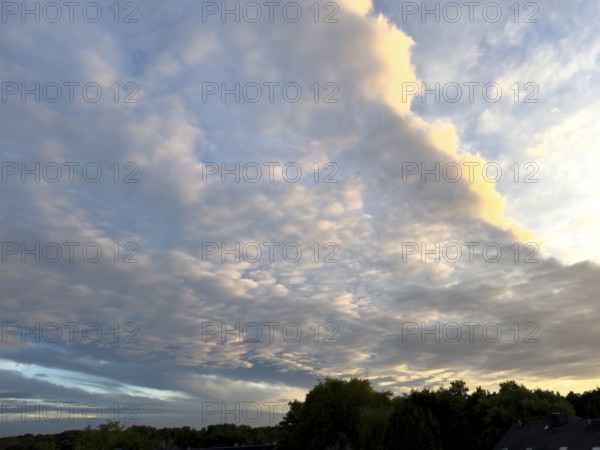 Cloud front with grey stratocumulus below right left and bright altocumulus clouds above