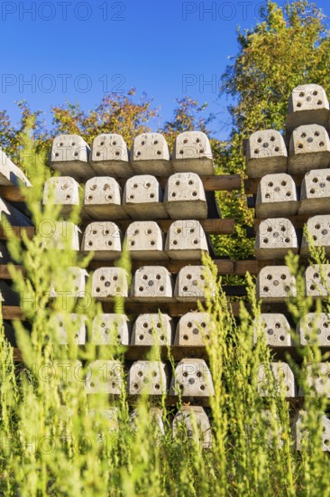 Many stacked concrete blocks with plants in the foreground, Hermann Hessebahn construction site,