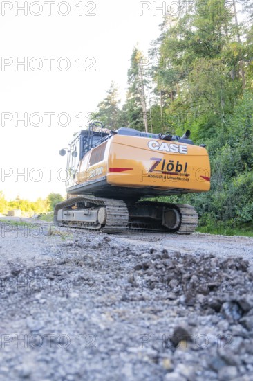 A large excavator on a construction site with trees in the background, Hermann Hessebahn