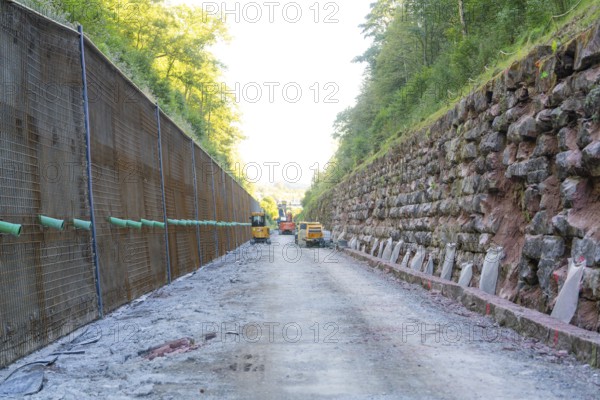 Machines on a construction site between steep walls overhung by trees, Hermann Hessebahn