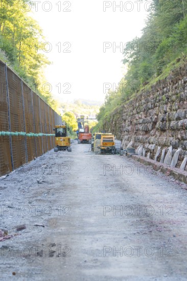Construction site with heavy machinery on a stony road between steep embankments, Hermann Hessebahn