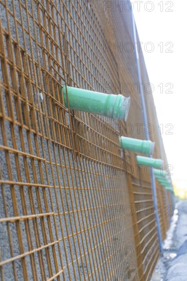 Side view of a construction wall with metal mesh and pipework, Hermann Hessebahn construction site,