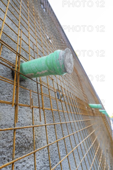 Close-up of a concrete wall with wire mesh and green pipes, Hermann Hessebahn construction site,