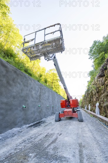 Lifting platform rises in front of concrete wall on construction site in the forest, Hermann
