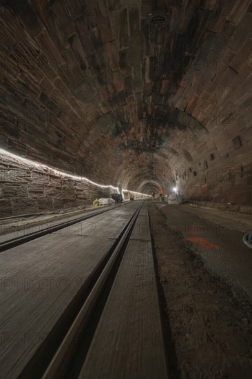 Dark tunnel with rails and lighting along the tunnel walls, construction of the Hermann Hesse