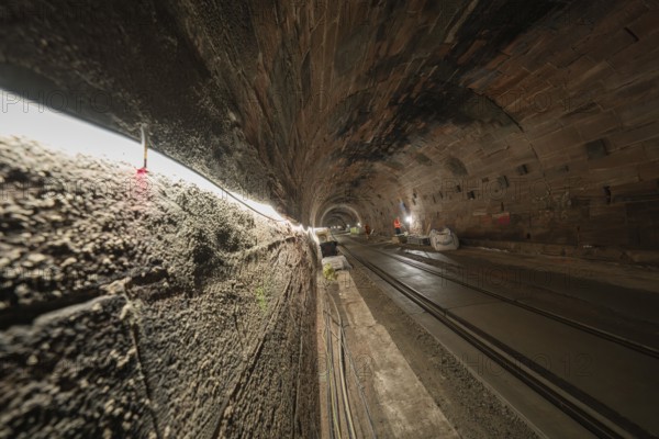 Tunnel with tracks and construction work, illuminated by line lights, construction of the Hermann